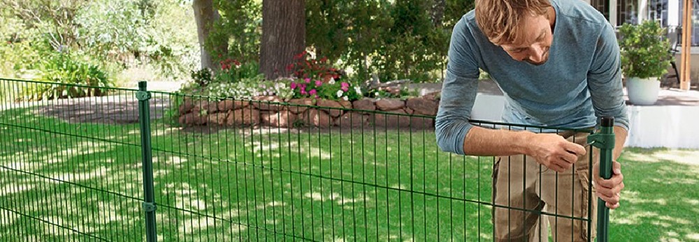 Person montiert grünen Metallzaun